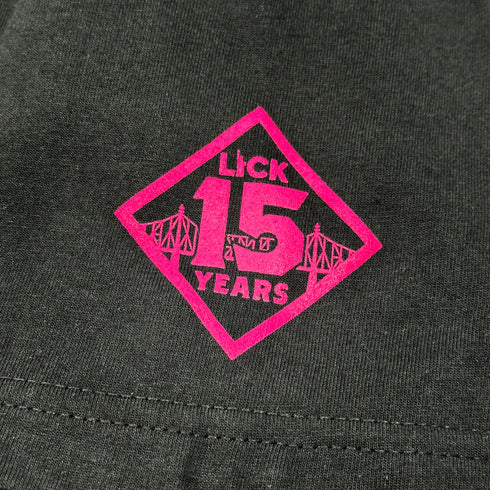 close up of pink 'Lick 15 Years' logo on sleeve of black shirt